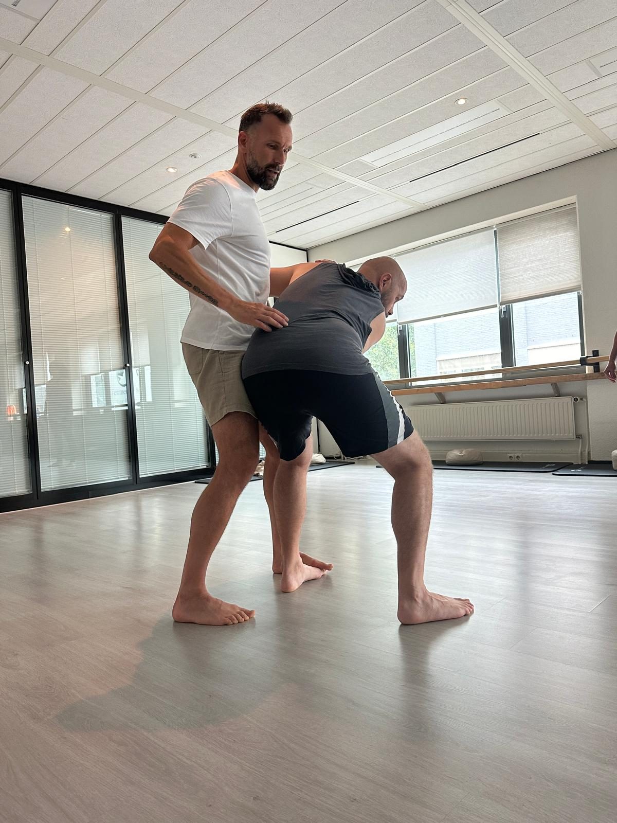 Gert begeleidt een deelnemer bij een beweging